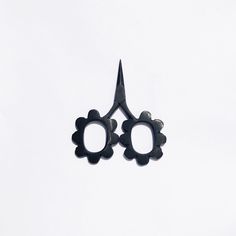 a pair of scissors with black handles are seen against a white sky background in this image