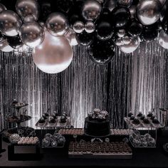 a table topped with lots of desserts and balloons hanging from the ceiling above it