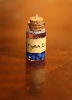 a bottle filled with blue beads sitting on top of a wooden table