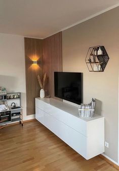 a flat screen tv sitting on top of a white entertainment center next to a wooden floor