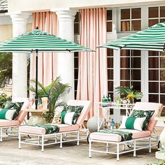 two chaise lounge chairs and an umbrella in front of a building with pink curtains