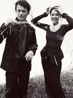 a man and woman standing next to each other on top of a grass covered field