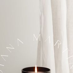 a lit candle sitting on top of a table next to a window with words written above it