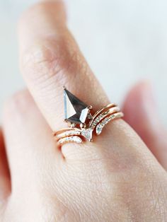 a woman's hand with a ring on it that has a triangle shaped stone in the middle