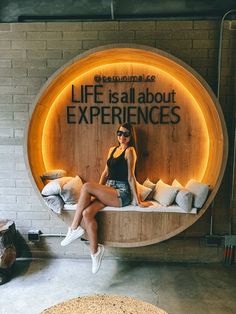 a woman sitting on a bench in front of a sign that says life is all about experiences