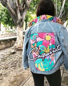 a woman wearing a jean jacket with the word charlotte painted on it