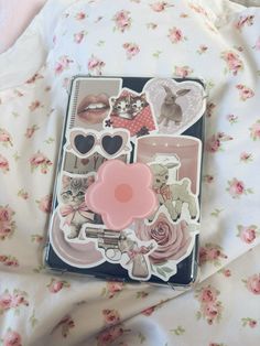 an open book with stickers on it sitting on a bed covered in pink flowers