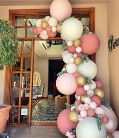 the balloon arch is decorated with pink, white and gold balloons