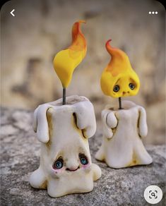 two small figurines sitting on top of a rock