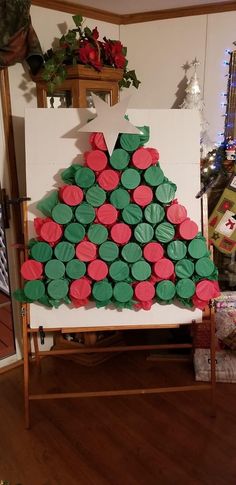 a christmas tree made out of cupcakes sitting on a easel in front of a christmas tree