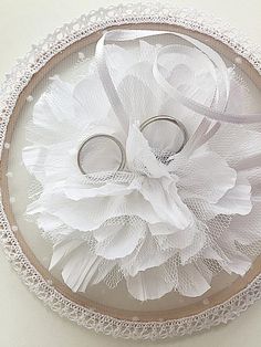 two wedding rings are placed on top of a lace doily decorated with white flowers