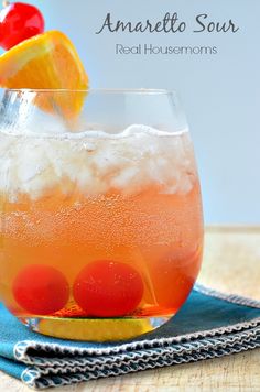 an orange drink in a glass with ice and garnish on the rim, sitting on a blue napkin