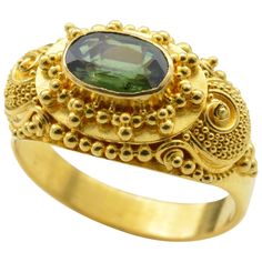 Intricate detail and spirals swirl around this deep green faceted tourmaline ring. Set in high carat 22K yellow gold this ring makes a statement fit for the Maharaja. Royal, regal and bright, the yellow gold glows in classical Indian fashion with the illuminating grassy green tourmaline ( aprox 1.0 ct). The wind-up piano box plays music and the lid to the keys lifts up uncovering the tiny golden keyboard. The ring size is 6.75 and can be sized to fit your finger. Luxury Oval Tourmaline Emerald Ring, Formal Tourmaline Rings For May Birthstone, Kemp Ring, Gold Ring Images, Haute Jewelry, Indian Rings, Jewelry Piercing, Contemporary Jewelry Design, Pink Sapphire Ring