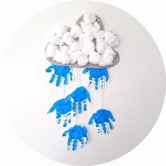 blue and white handprinted clouds are hanging on a wall with cotton balls in the shape of elephants