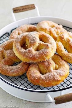 powdered sugar donuts on a cooling rack with cinnamon sticks in the back ground