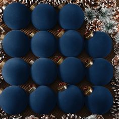 blue balls and pine cones are arranged on a table