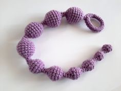 a purple crocheted bracelet with two knoted balls on the end and one knot in the middle