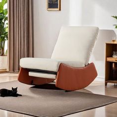 a black cat laying on the floor next to a white recliner chair and rug