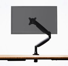 a computer monitor mounted to the side of a desk with a black arm on it