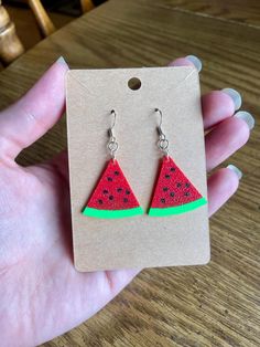 a pair of watermelon slice earrings is shown in front of a cardboard card