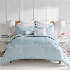 a bed with blue comforter and pillows in a room next to a white wall