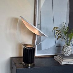 a table lamp sitting on top of a book shelf next to a vase filled with flowers