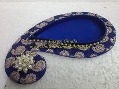 a pair of blue shoes with pearls on the soles and an embellished brooch