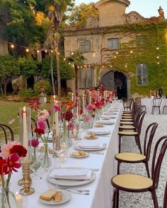 a long table is set up with flowers and candles for an outdoor wedding reception at dusk