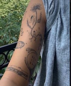 a person with a tattoo on their arm next to some bushes and trees in the background