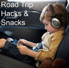 a young boy sitting in the back seat of a car wearing headphones and looking at his phone