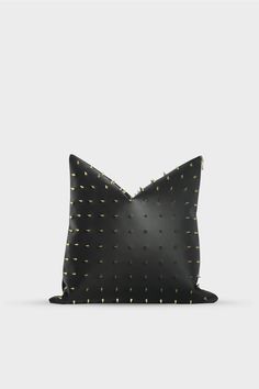 a black pillow with gold dots on the front and back, sitting on a white surface