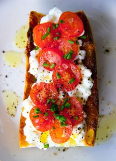 a piece of bread topped with tomatoes and cottage cheese on top of buttered bread