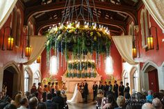 a couple getting married in front of an altar with flowers and candles hanging from the ceiling