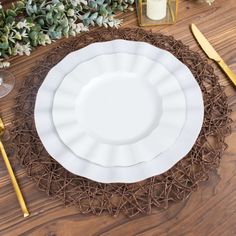 a white plate sitting on top of a wooden table next to gold utensils