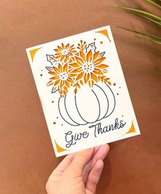 a person holding up a card with flowers in the center and give thanks written on it