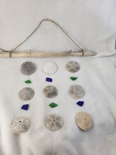 a group of sea glass and sand dollars on a white sheet with a wooden stick