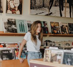 a young woman standing in front of a record store counter with records on the wall