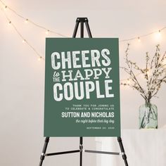 a sign that says cheers to the happy couple sitting on top of a easel