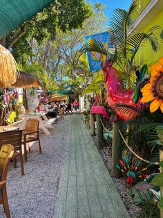 tables and chairs under umbrellas on the side of a building with flowers in it