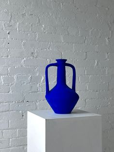 a blue vase sitting on top of a white block