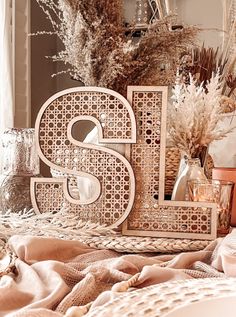 decorative wooden letters sitting on top of a bed next to dried plants and vases