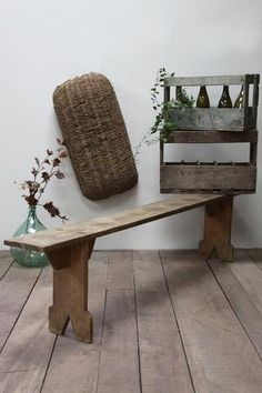 a wooden bench sitting on top of a hard wood floor next to a vase filled with flowers