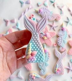 a hand is holding a cookie shaped like a mermaid's tail and under the sea