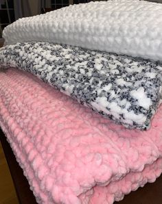 three blankets stacked on top of each other in pink, white and grey colors with black speckles