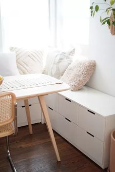 a room with white furniture and plants in the window sill next to a table