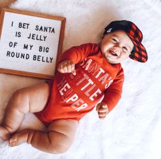 a baby is smiling next to a sign that says, i bet santa is jelly of my big round belly