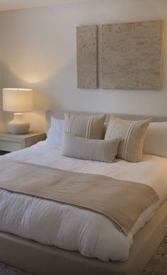 a bed with white linens and pillows in a small room next to two lamps