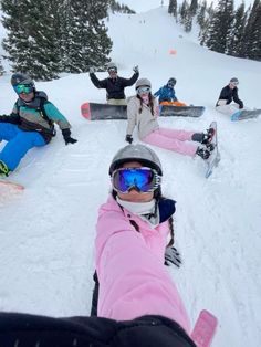 a group of snowboarders sitting in the snow with their feet on the ground