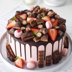 a cake with chocolate, strawberries and other toppings sitting on a white plate