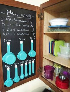 a chalkboard with measuring spoons and cups on it next to shelves filled with dishes